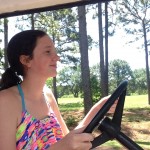Natalie happily driving the golf cart