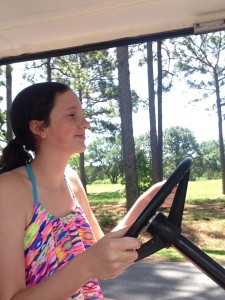 Natalie happily driving the golf cart